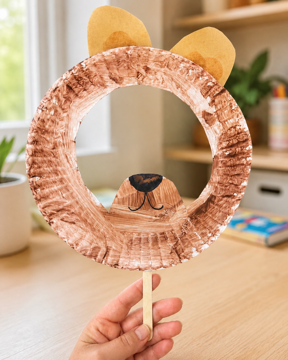 Paper plate bear mask craft with ears and a craft stick handle